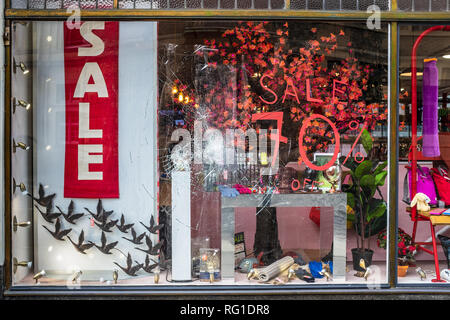 Broken Shop Window - Sale 70% off - a shop window displaying sale information is broken by vandals Stock Photo