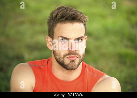 Taking minute break. Runner relaxing in shadow. Man with bristle strict face, grass background. Man unshaven looks handsome and cool. Guy bearded and attractive relaxing at meadow during workout. Stock Photo