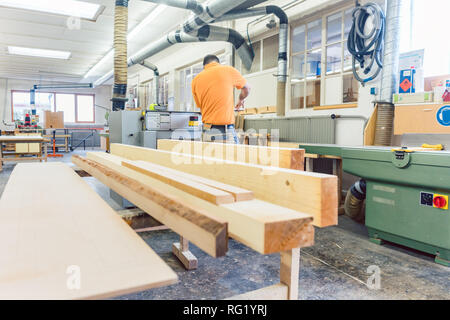 Carpenter or joiner working on logs in his workshop