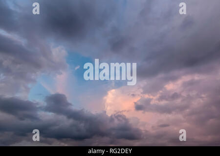 Beautiful cloudscape with pink and dark grey clouds and a little blue sky. Stock Photo