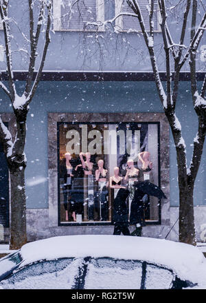 Two people walking past shop window with mannequin display, during snowstorm, Avezzano, Abruzzo region, Italy, Europe Stock Photo