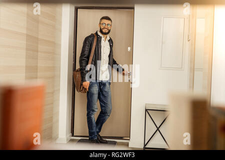 Handsome short-haired bearded man with a bag leaving the room Stock Photo