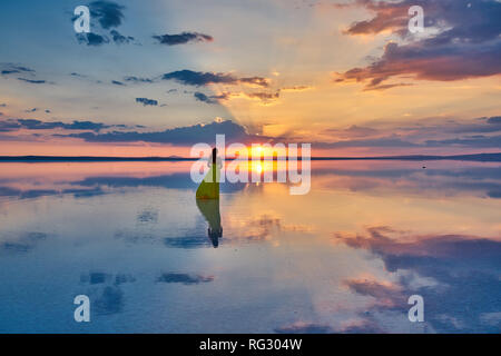 Yellow dressed model at sunset, on the salt lake (Tuz Gölü), Turkey. Stock Photo