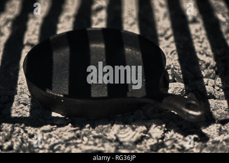 Black cast iron skillet preheating on the embers and ashes under a grill, province of Buenos Aires, Argentina. Close up scene. Barbecue background. Stock Photo