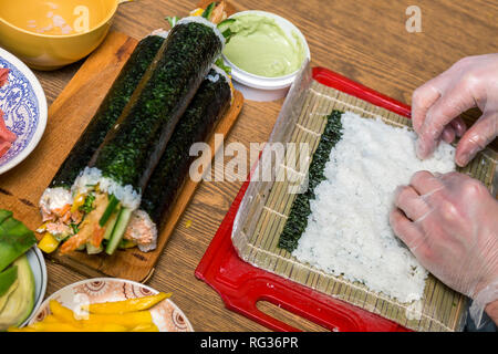 The process of making Japanese sushi. Knife in hand cuts a roll close-up on  a wooden board Stock Photo - Alamy