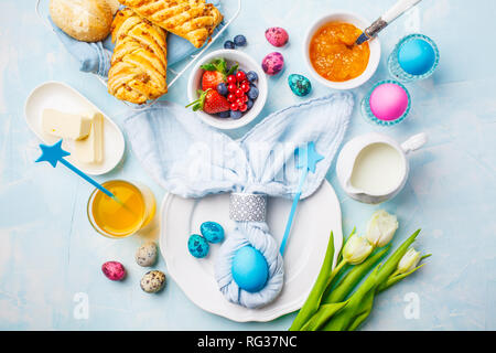 Easter Breakfast table. Blue background, festive table setting, top view. Stock Photo