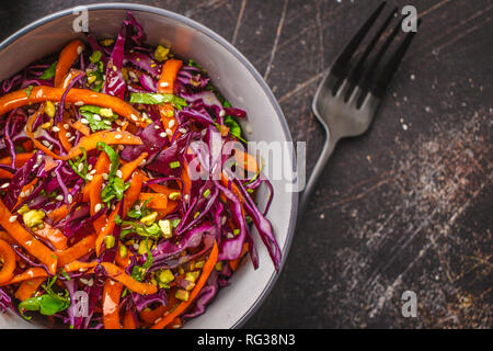 Coleslaw salad in a gray bowl on a dark background. Red cabbage and carrot salad. Stock Photo