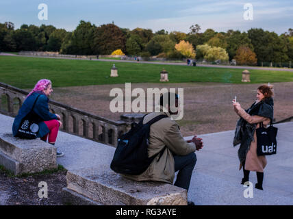 Young woman photographing friend using smartphone, at the grand terraces, Crystal Palace, London, England, UK Stock Photo