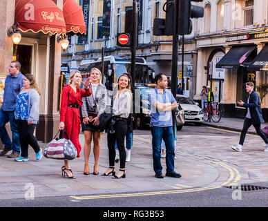 Female friends, standing on pavement beside road, deciding which way to go, Central London, England, UK Stock Photo