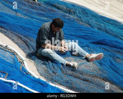 ESP, Spain, Balearic Islands, Mallorca : Fisherman patches fishing nets in Port de Soller. Stock Photo