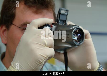 DEU, Germany, NRW: Forensic police investigator takes photos at a crime scene, with a digital camera. Stock Photo