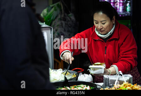 London, England - January 20, 2019. Food vendors prepare authentic offerings for shoppers and tourists inside Camden Market. Stock Photo