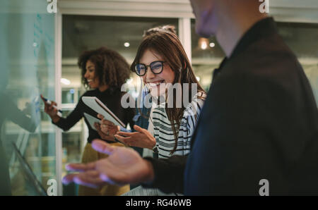 Female student chatting with classmate in classroom. Cheerful students at educational workshop. Stock Photo