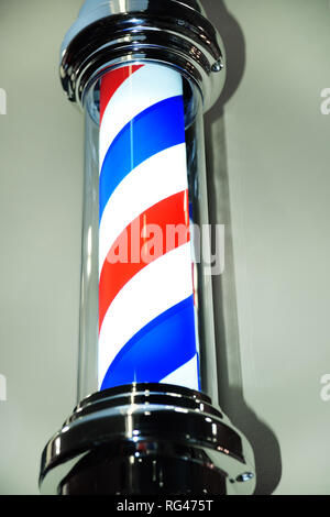 striped blue red Barber pole close-up on grey background. Stock Photo