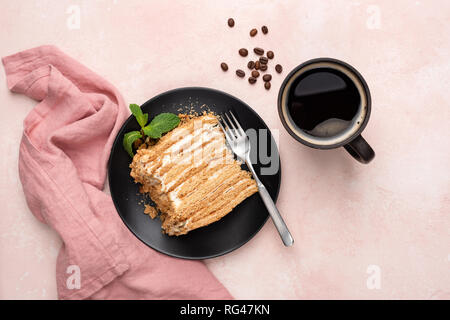 Layered honey caramel cake Medovik and cup of black coffee on pink background, table top view, flat lay food styling Stock Photo