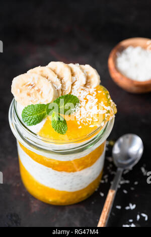 Chia Pudding With Mango Mousse And Coconut In Jar. Healthy food Stock Photo