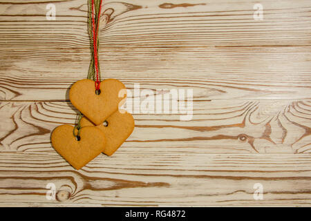 Handmade heart shaped cookies, tied to a rope on a wooden background  for a Valentine, Christmas or any holiday of loving people Stock Photo