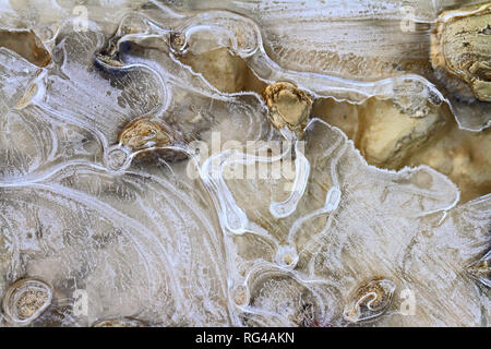 macro of an icy puddle or ice patterns on a gravel driveway in winter in Italy Stock Photo