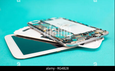 Tablet repair. Close-up disassembled mobile phone parts. Colorful blue background. Stock Photo