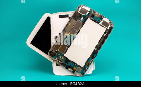Tablet repair. Close-up disassembled mobile phone parts. Colorful blue background. Stock Photo