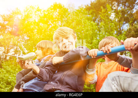 Happy children climb on climbing frame in playground in summer Stock Photo