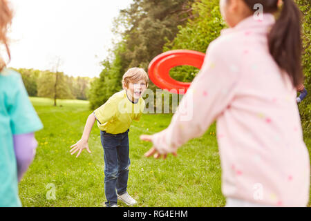 Group of kids playing frisbee in the park in kindergarten or on vacation Stock Photo