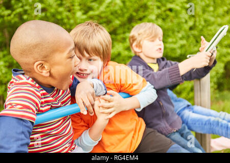Kids as friends together on a jungle gym in summer vacations Stock Photo