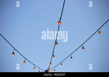 Light bulbs on string wire with sky Stock Photo