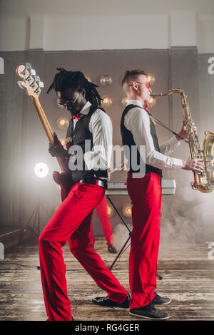 Caucasian man playing acoustic guitar while woman playing saxophone. Stock Photo