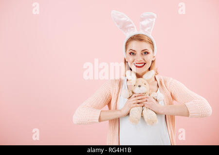 happy woman in bunny ears with toy. Woman in rabbit bunny ears. Happy easter. Spring holiday. Girl with hare toy. Egg hunt. Easter eggs as traditional Stock Photo