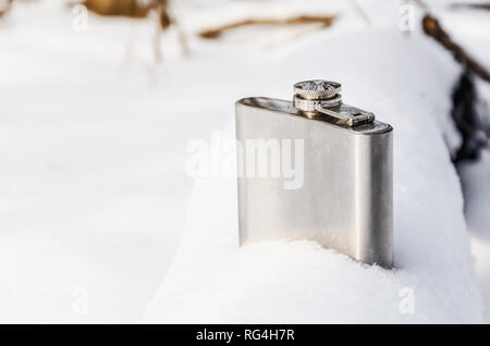 Metallic shiny flask for alcohol in snow. Nature, winter, rest. Stock Photo