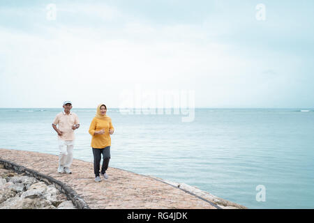 senior man and woman together running on the beach Stock Photo