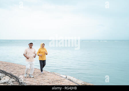 senior man and woman together running on the beach Stock Photo