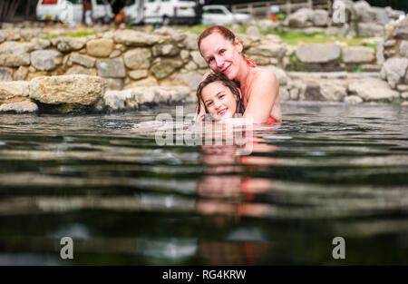 Mother and daughter relaxing in natural thermal water roman spa. Family retreat at outdoor pools and baths with hot, smoking thermal water and hot spr Stock Photo