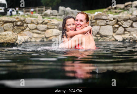 Mother and daughter relaxing in natural thermal water roman spa. Family retreat at outdoor pools and baths with hot, smoking thermal water and hot spr Stock Photo