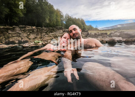 Man and woman relaxing in natural thermal water roman spa. Happy couple in outdoor pools and baths with hot, smoking thermal water and hot spring of A Stock Photo