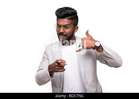 Call me back please. Young attractive hipster indian man, makes phone sign, indicates with index finger directly at camera, wants to speak with someon Stock Photo