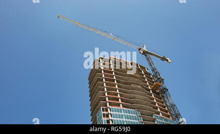 Construction of a new high rise building with a crane and bright blue sky for background. Stock Photo