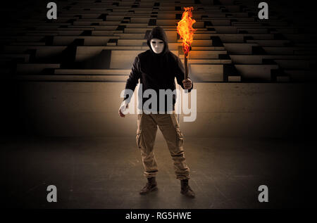 Ugly, aberrant man coming out from the labyrinth with burning flambeau on his hand  Stock Photo