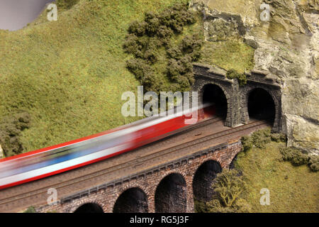 Electric Model Train on miniature train track going through mountain tunnel Stock Photo