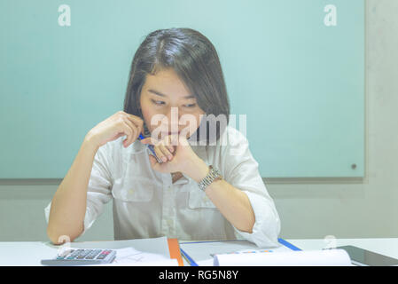 Young Asian woman reading financial reports and thinking Stock Photo
