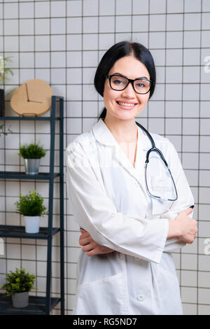 Beautiful smiling doctor wearinbg glasses standing in her modern office Stock Photo