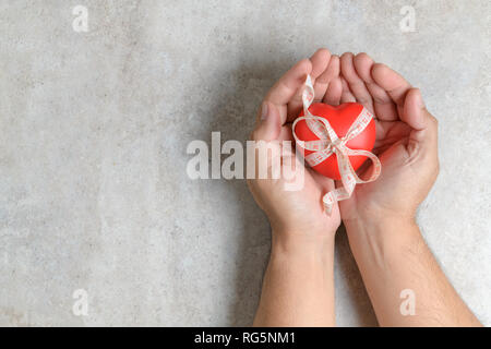 Man holding a red heart shape on marble table. Healthy balance and lose weight concept Stock Photo