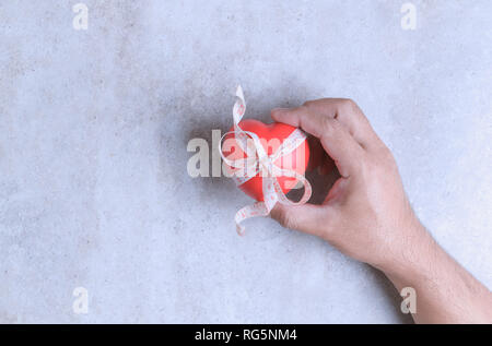Man holding a red heart shape on marble table. Healthy balance and lose weight concept Stock Photo