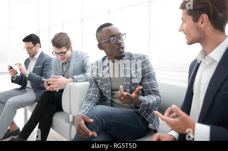 employees of the company are talking sitting in the lobby of the office Stock Photo