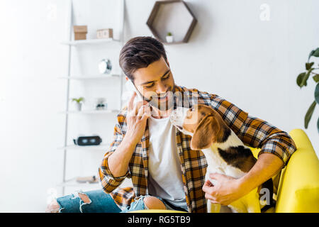 handsome smiling man talking on smartphone and looking at dog Stock Photo