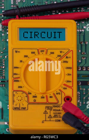 Digital multimeter multitester on a circuit board with the word circuit on the display Stock Photo