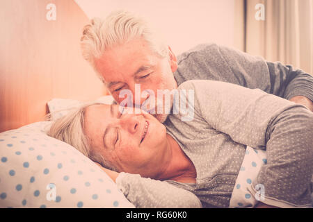 Couple of senior caucasian man and woman kissing in early morning at the bed at home for love everyday with no limit age - foreverness together concep Stock Photo