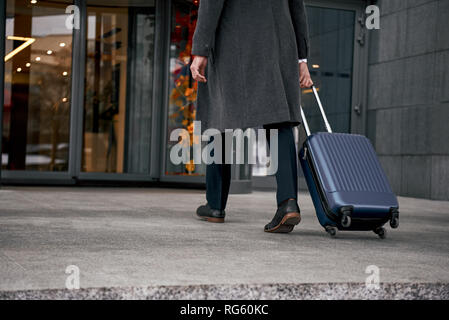 Close up of man carrying suitcase at the airport terminal and hurrying up for check in on holiday or business trip. Stock Photo