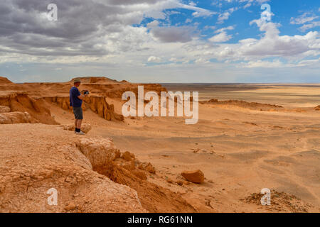 Man standing in desert taking a photo, Flaming Cliffs, Gobi Desert, Bulgan, Mongolia Stock Photo